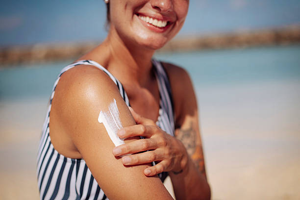 istock Smiling Woman Applying Sun Cream on Beach 2218763681