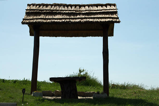 A gazebo in a grassy field. Text. Grass. Sky. Outdoor. Wooden