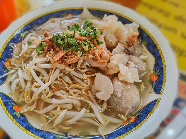 vietnamse noodle soup, served with fresh herbs at the buddhist eatery, radish, morning glory, shiitake and tofu in white bowl on Wood table in Vegetarian Festival.