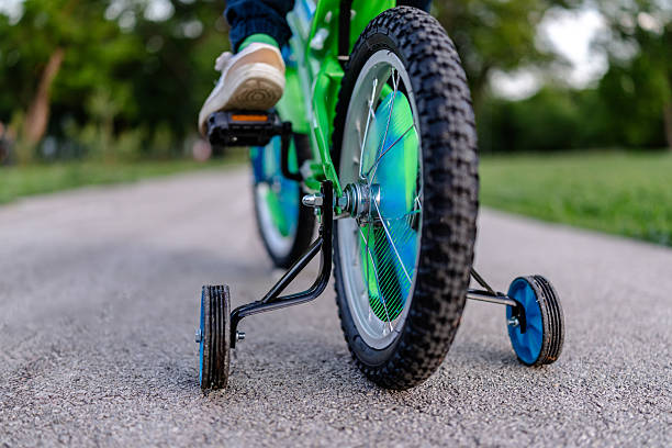 istock Boy happily riding a green bicycle through a lively park during springtime 2218779133