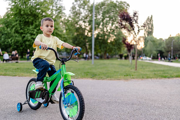 istock Boy enjoys riding his green bicycle in a public park during springtime 2218779362