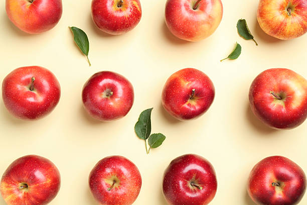 istock Many red apples and green leaves on beige background, flat lay 2218780991