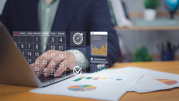 Hand on laptop with digital calendar, target, charts. Symbolizes digital scheduling, project planning, goal setting. Ideal for business management, productivity, data analysis, strategic execution now