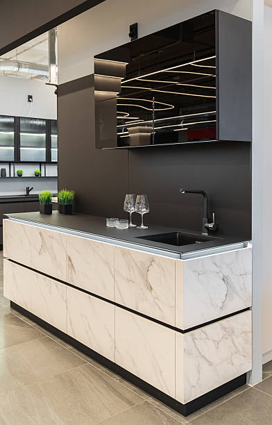 istock small built-in black and white kitchen. upper and lower cabinets. white countertop, black sink and faucet. Glass doors on upper cabinets. built-in furniture. 2218786834
