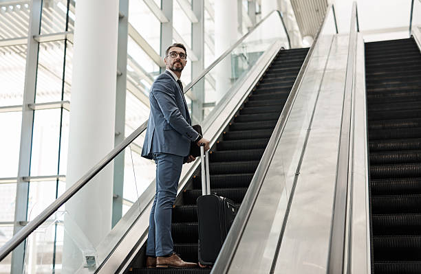 istock Businessman with Luggage Using Escalator in Modern Airport Terminal 2218789608