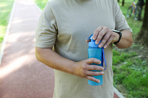 istock Man Holding a Plastic Bottle of Water in a Park 2218790144