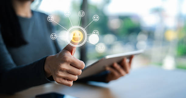 istock A person gives a thumbs up while holding a tablet, with a digital smiley face and feedback icons overlayed. 2218790357