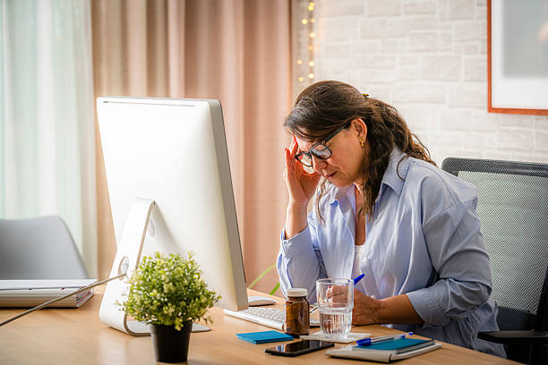 istock Woman sitting by the office desk having a headache 2218795544
