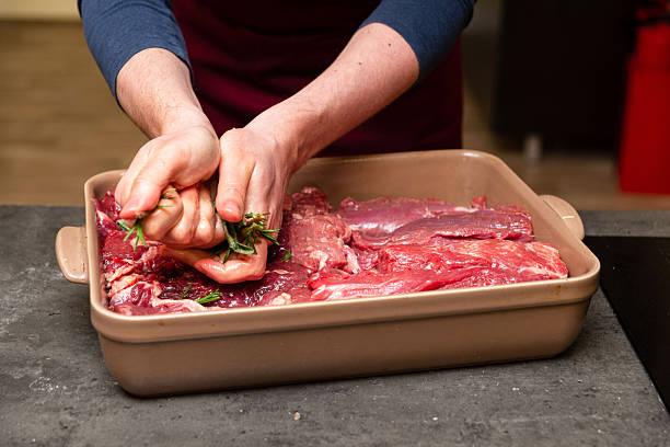 istock Chef Marinating Raw Beef Steaks with Fresh Herbs. 2218795918