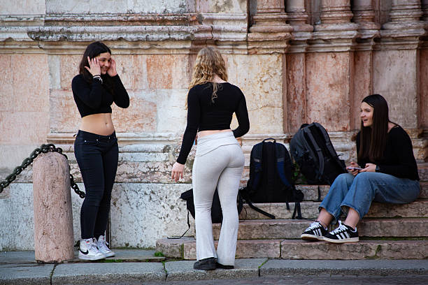 Parma, Italy, April 4, 2025: Friends in trendy outfits relaxing on steps enjoying conversation city vibes.