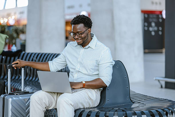 istock Professional man using laptop on bench at public station with suitcase nearby 2218800038