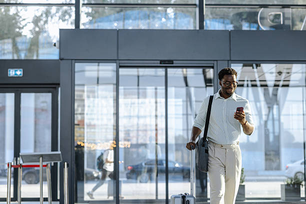 istock Smiling traveler using phone while walking through modern public transportation terminal 2218801288