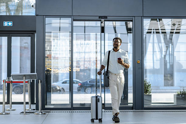 istock Smiling traveler pulling suitcase and holding a smartphone at modern transportation terminal 2218801293