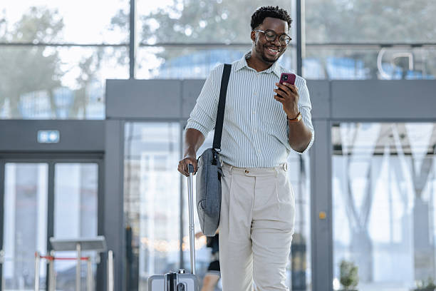 istock Smiling traveler using phone while walking through modern public transportation terminal 2218801321