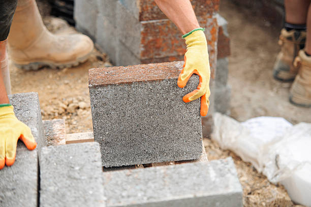 istock Example of manual handling as bricklayers moving concrete footing blocks by hand on building site 2218803685