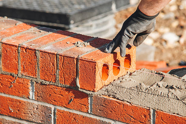 istock Close-up of skilled bricklayer working on construction site laying red bricks for wall construction while 2218804170