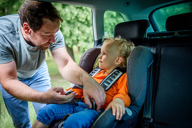 istock Toddler frowns while dad buckles him into car seat. 2218806853