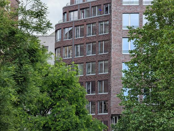Modern brick building with large windows surrounded by urban greenery