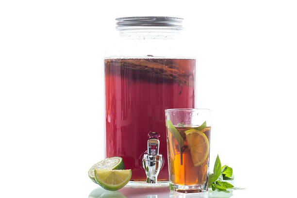 Golden kombucha with bubbles and greenery on white background.