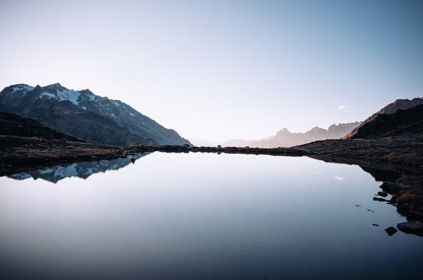 Breathtaking mountain road winding through the Susten Pass in the Swiss Alps, captured on a scenic summer road trip. Dramatic alpine peaks, lush green valleys, and clear blue skies create a stunning natural landscape. Ideal for travel, adventure, freedom, and nature concepts.
