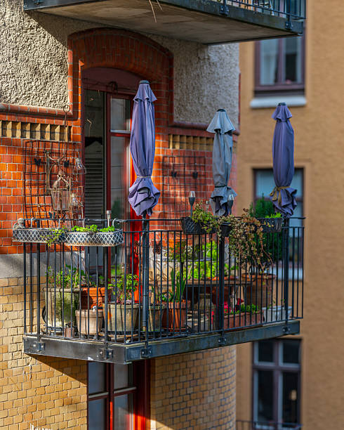 Small balcony with potted plants and closed umbrellas