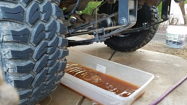 Draining the Antifreeze on a 1990s Vehicle with Big Tires into a Plastic Bin