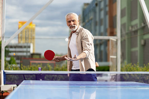 istock Senior man playing ping pong outdoors having fun 2218823001