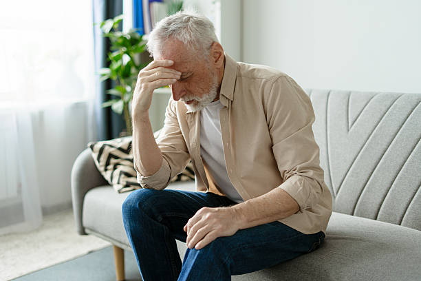 istock Senior man sitting on sofa at home suffering from headache 2218823019