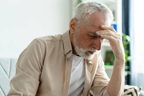 istock Senior man suffering from headache, touching forehead sitting on sofa at home 2218823022