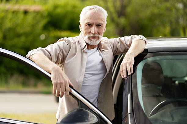 istock Senior man leaning on his new car is looking at camera 2218823039