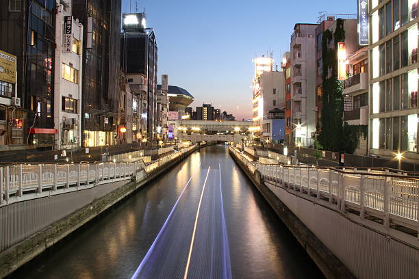 A vibrant night scene of Osaka’s famous Dotonbori district, featuring the illuminated canal flanked by colorful neon signs and bustling buildings. The glowing reflections on the water capture the dynamic energy and iconic nightlife of this lively entertainment hub in Japan.