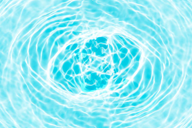 Blue water with ripples on the surface. Defocus blurred transparent blue colored clear calm water surface texture with splashes and bubbles. Water waves with shining pattern texture background.