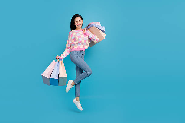 istock Photo of shiny adorable lady dressed print pullover jumping holding shoppers empty space isolated blue color background 2218840230