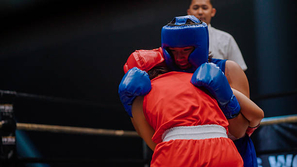 istock Young female boxer in blue helping her opponent up after knocking her down. 2218854890