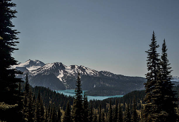 istock Snow-Capped Mountains and Turquoise Lake Framed by Tall Trees 2218859868