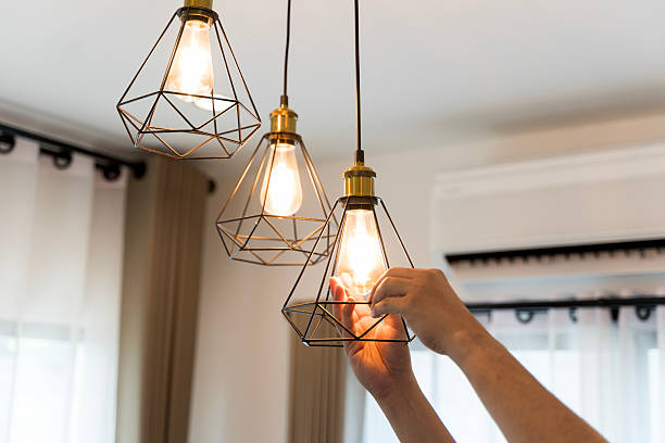 istock Hand changing light bulb in modern pendant lamp with geometric metal frame, energy saving home interior concept 2218861420