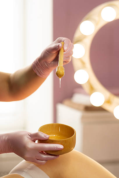 istock Honey slowly dripping from wooden stick during spa session. 2218863625