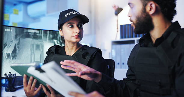 istock Night, security team and discussion in control room for feedback, advice or standard procedure with tablet. Man, woman guard or paperwork in office for protocol rundown, service or tech on late shift 2218866262