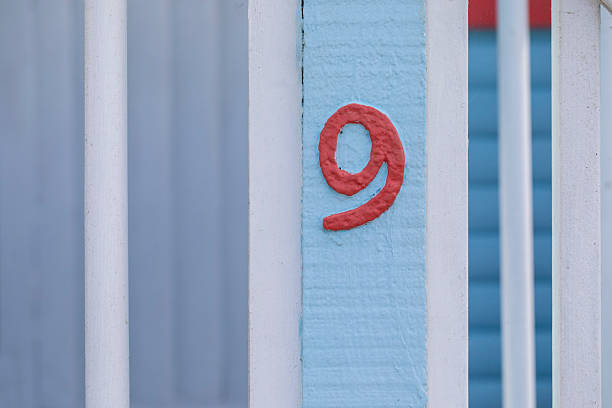 Red number 9 on a wooden fence to a beach hut