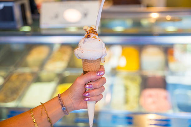 Woman holding delicious ice cream cone in gelateria display case