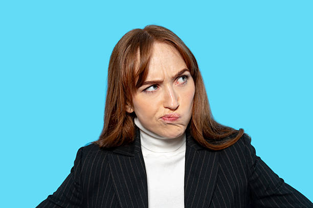 A woman wearing a striped blazer and turtleneck shows a perplexed expression, likely in response to a puzzling question or situation. The blue background adds contrast.