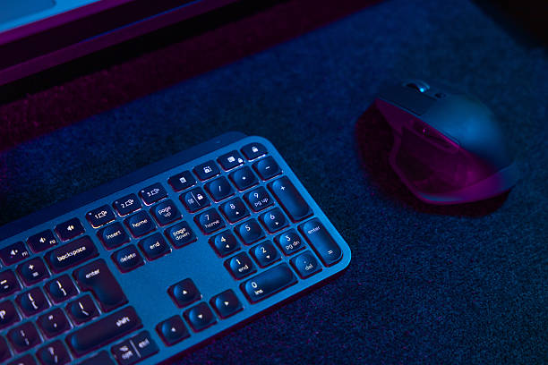 istock Backlit Gaming Keyboard and Mouse with Blue and Purple LED Lights in Dark Tech Setting 2218871480