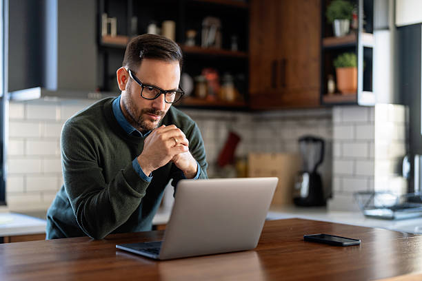 istock Satisfied man using laptop computer for electronic banking, making reservation, online shopping 2218873879
