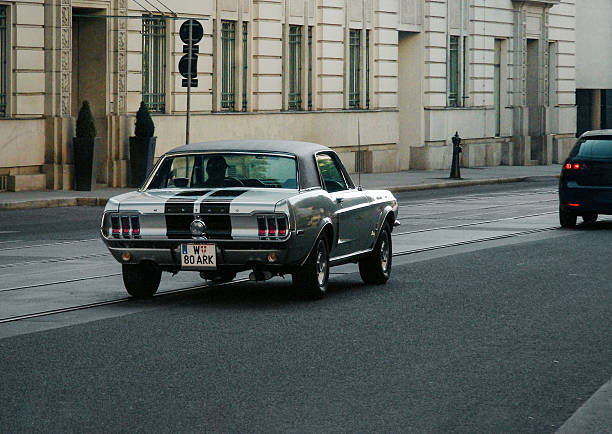 Silver Ford Mustang driving down the street. Three quarter rear view of old, 1960s american pony car on a street in Vienna, Austria on August 02 2010. driving horse stock pictures, royalty-free photos & images