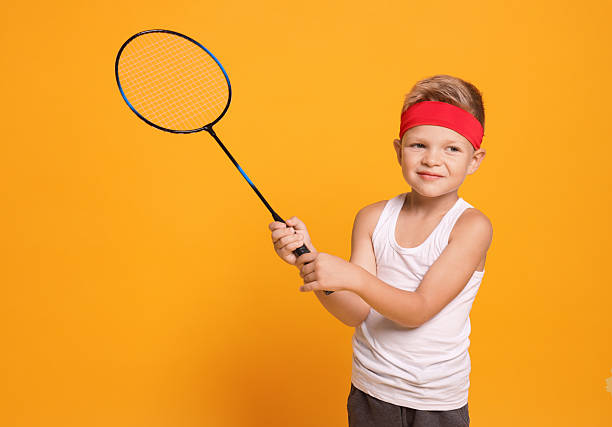 istock Little boy with badminton racket on orange background 2218874029