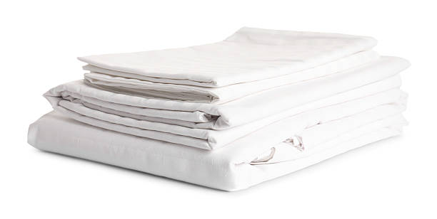 Stacked clean bed linens on white background