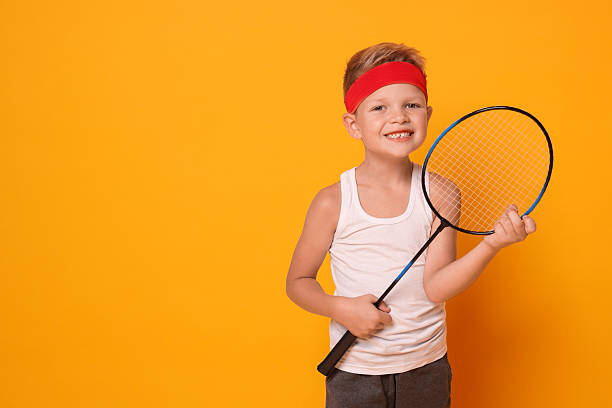 istock Little boy with badminton racket on orange background, space for text 2218874199