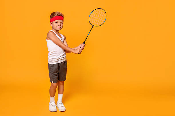 istock Little boy with badminton racket on orange background, space for text 2218874210