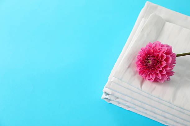 istock Stacked clean bed linens and pink flower on light blue background, top view. Space for text 2218874274