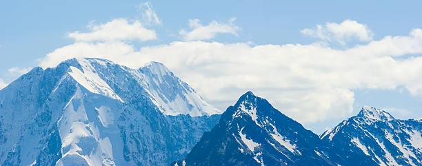 mountain ridge in snow under a blue cloudy sky, summer mountain travel scene